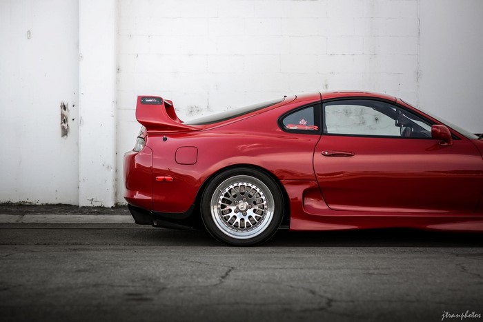Red Toyota Supra with spoiler and custom wheels