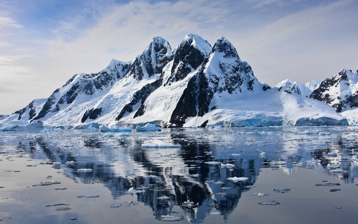 Snow-covered mountains reflected in icy water