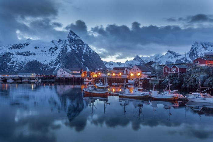 Fishing village and snow-capped mountains at dusk