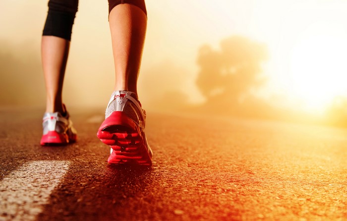 Runner's legs and feet on a road at sunrise