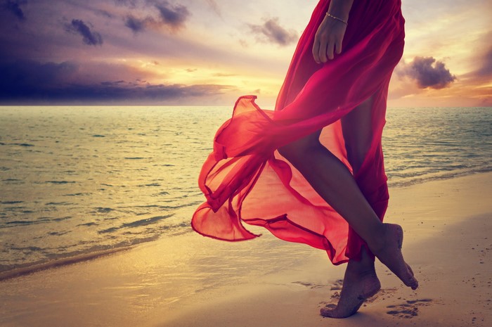 Woman in red dress on beach at sunset
