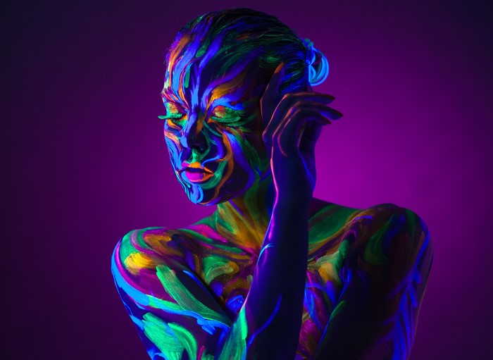 Woman with colorful body paint under blacklight