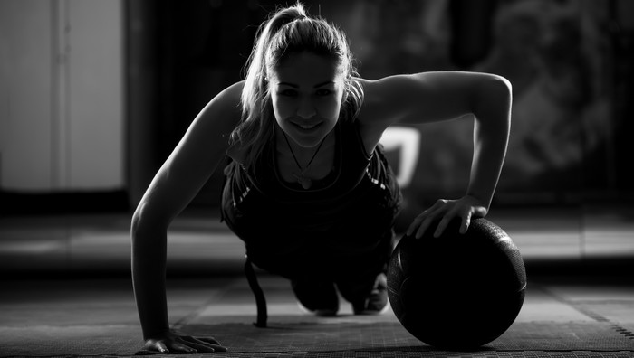 Woman doing push-ups with a medicine ball