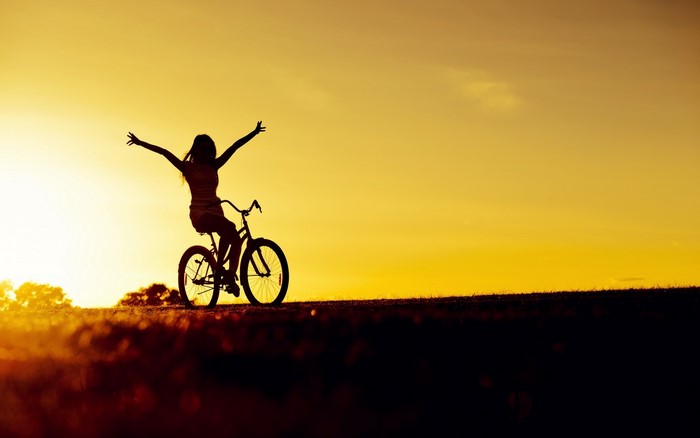 Silhouette of a woman on a bicycle at sunset