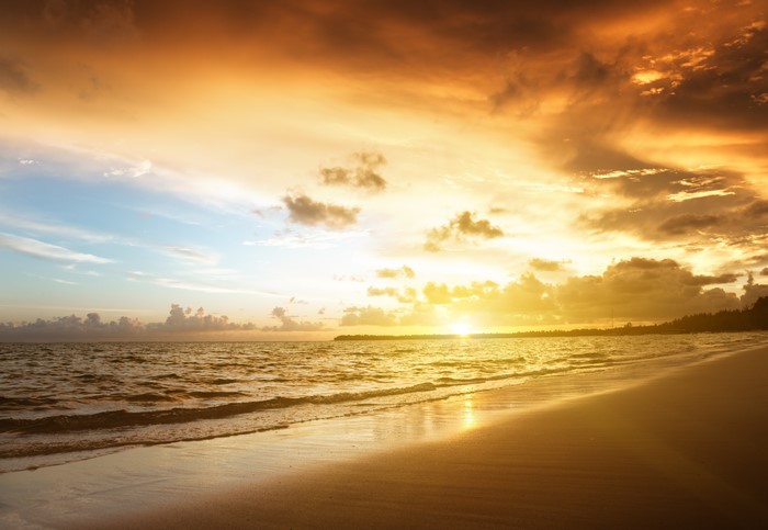 Sunrise over a tropical beach with ocean waves