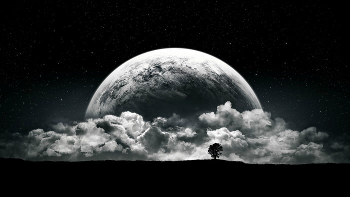 Dark night sky with a large moon and clouds over a silhouette landscape with a tree
