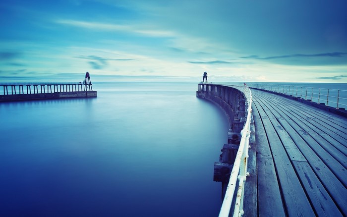 Wooden pier with lighthouses on the sea horizon