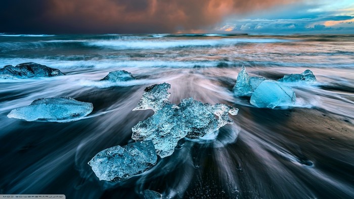 Ice chunks on black sand beach with ocean waves in Iceland
