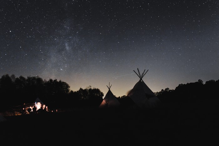Tipi camp under a starry night sky