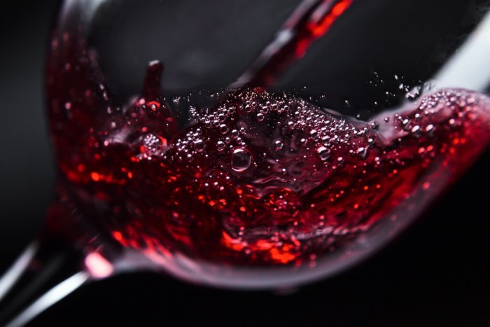 Red wine being poured into a glass with bubbles