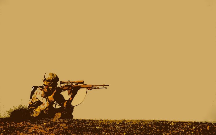 Soldier aiming a sniper rifle in a field