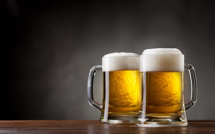 Two mugs of beer with foam