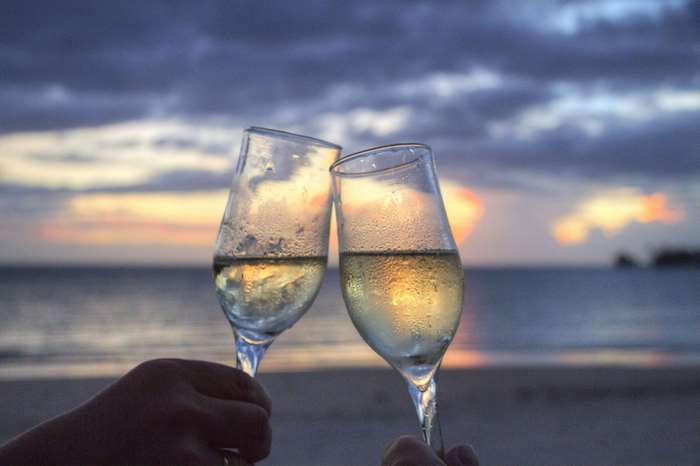 Champagne glasses clinking at sunset on a beach