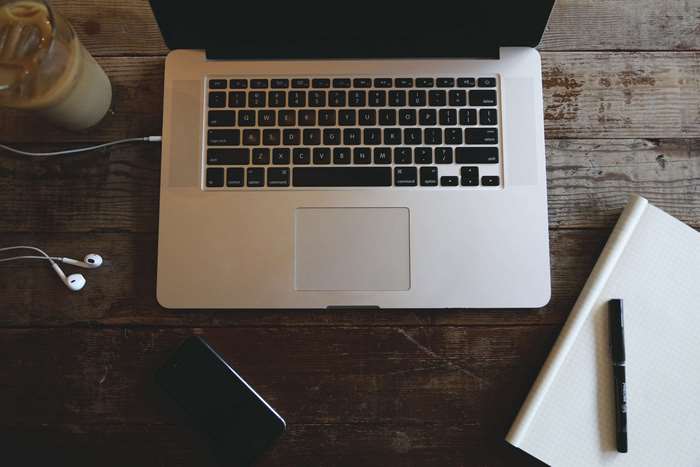 MacBook Pro with coffee, headphones, and notebook