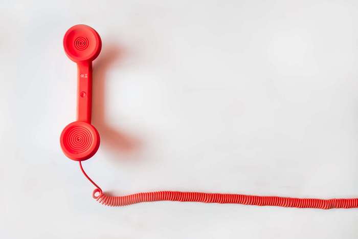 Red telephone handset with coiled cord on white background