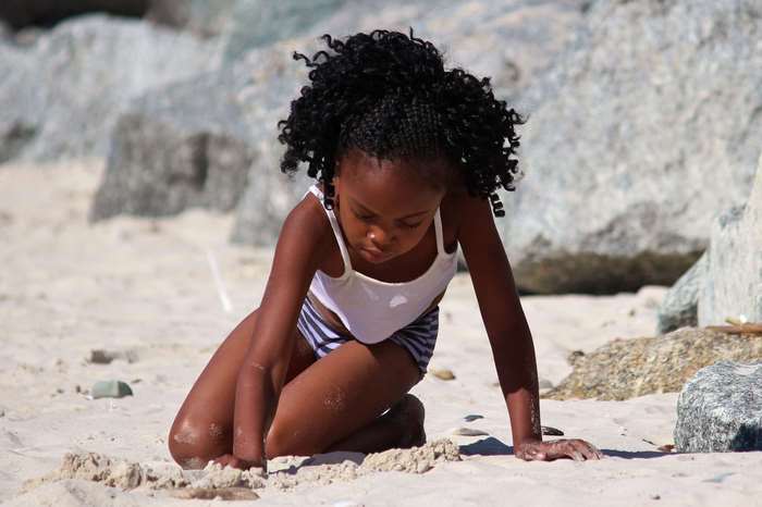 Young Black girl playing in the sand on a beach