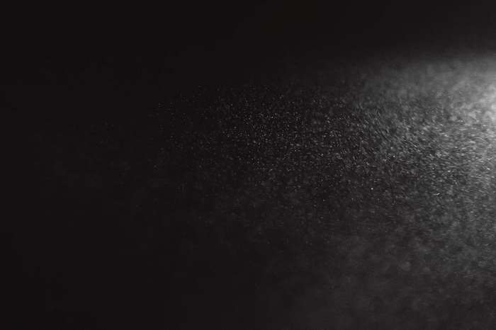 White dust particles illuminated by light on black background