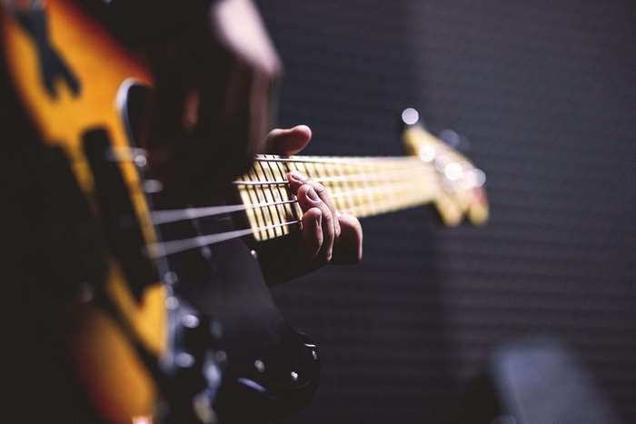 Close up of hands playing a bass guitar