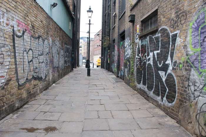 Graffiti-covered alley with a lamppost and yellow van