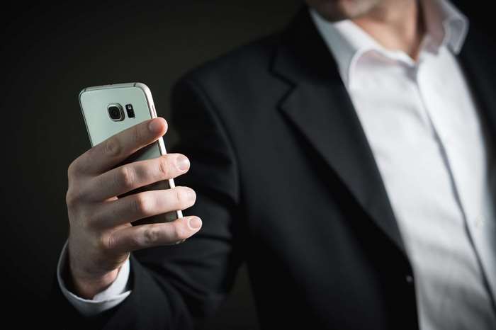 Man in Suit Holding a Smartphone