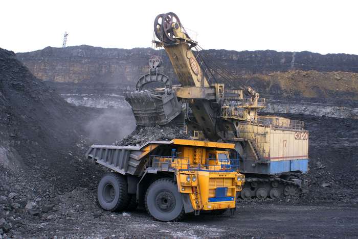 Giant excavator loading coal into a dump truck in a mine