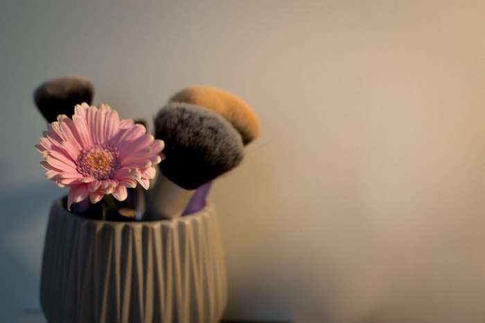 Pink gerbera daisy with makeup brushes in a vase