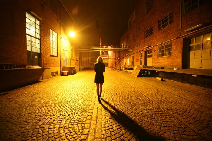 Woman walking down a cobblestone street at night