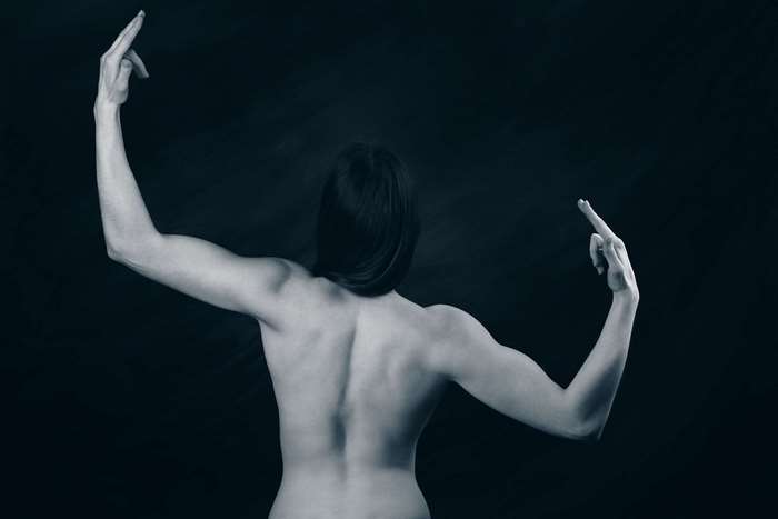 Woman with muscular back and arms raised