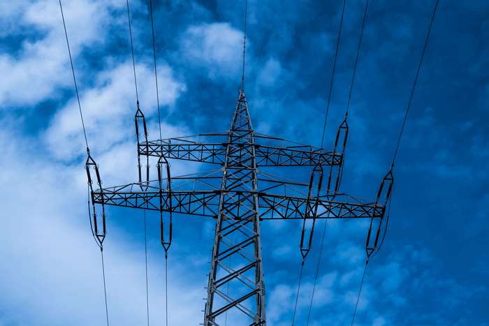 High voltage power line pylon against blue sky