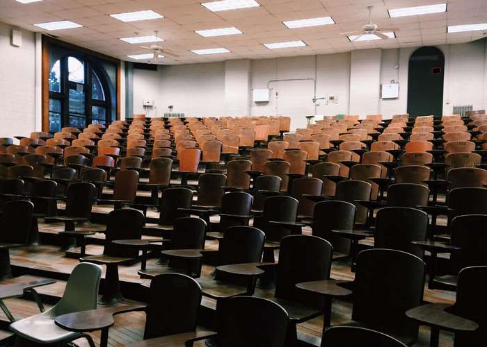 Empty lecture hall with tiered wooden seats and desks