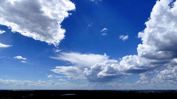 Blue sky with clouds over a dark landscape