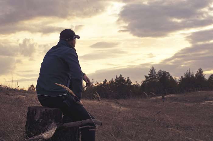 Man sitting on a tree stump at sunset