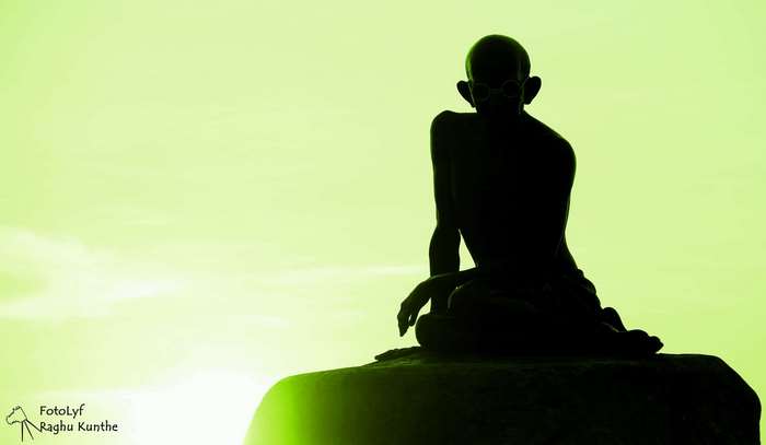 Silhouette of Mahatma Gandhi sitting on a rock