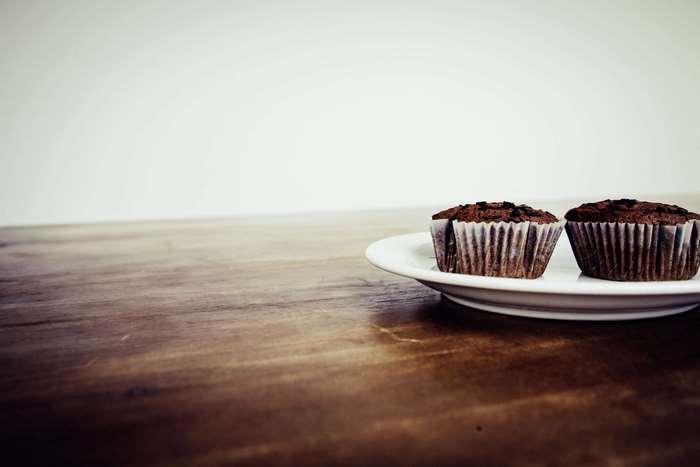 Two chocolate cupcakes on a plate on a wooden table 4K