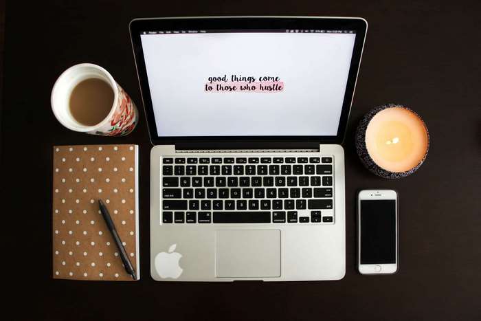 MacBook Pro with coffee, notebook, phone, and candle