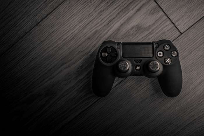 Black PlayStation 4 controller on wooden surface