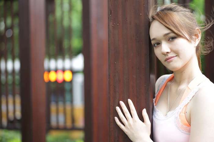 Young woman leaning against wooden pillars outdoors