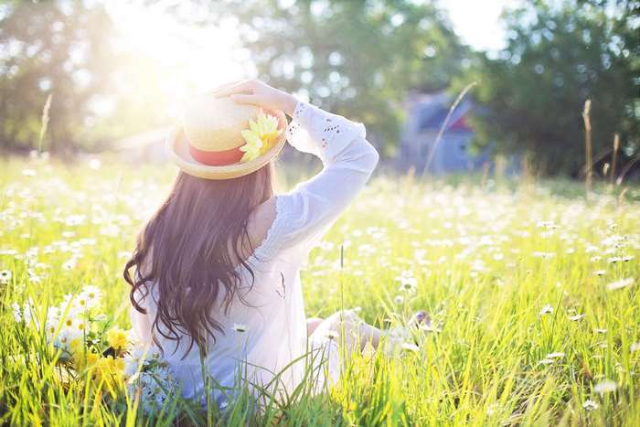 Woman in a hat sitting in a sunny meadow
