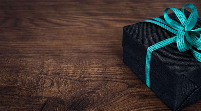 Black gift box with teal ribbon on wooden table 4K