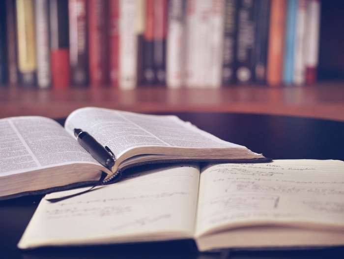 Open books and notebook with pen on a table