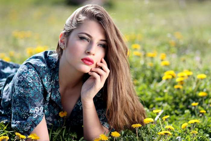 Woman in a floral dress lying in a field of dandelions