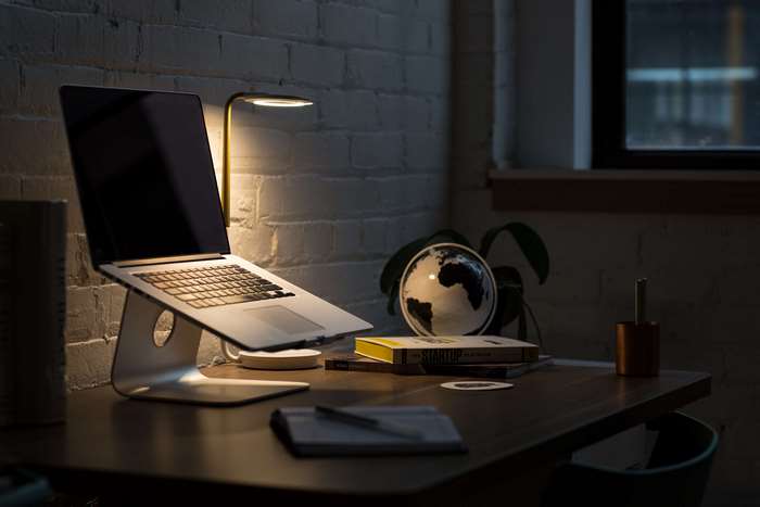 MacBook on a desk with a lamp and globe