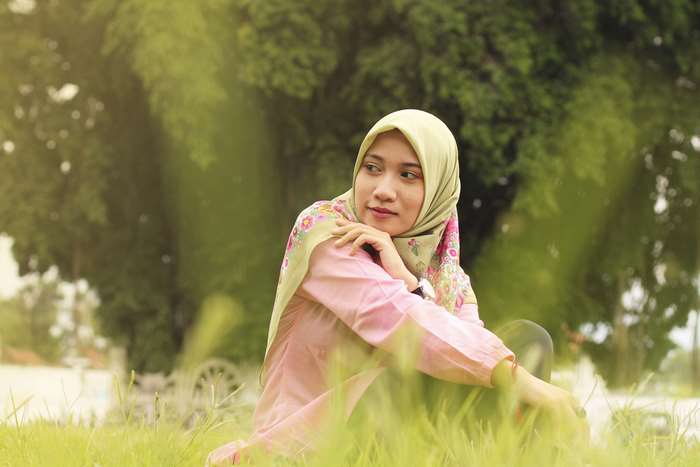 Serene Hijab Girl Sitting in Green Grass 4K
