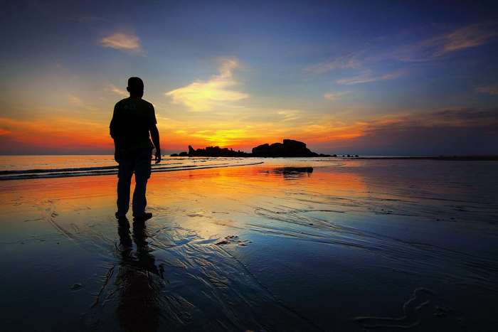 Man silhouetted on a beach at sunset