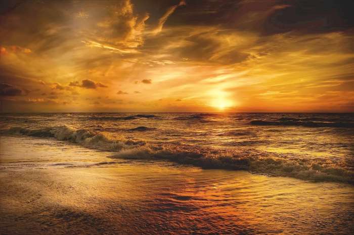 Ocean waves at sunset with golden clouds