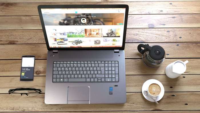 Laptop, smartphone, coffee, and eyeglasses on a wooden table