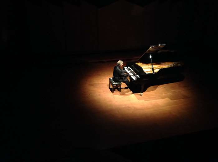 Pianist playing a grand piano on a stage