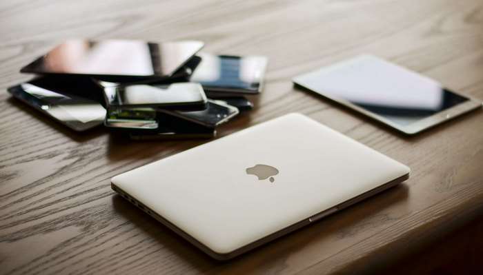 Apple MacBook, iPads, and smartphones on a wooden table