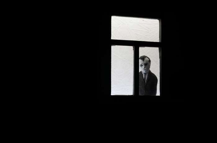 Man in suit peeking through a window