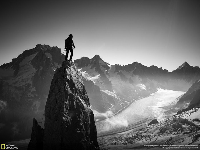 Man on mountain peak with glacier and mountains